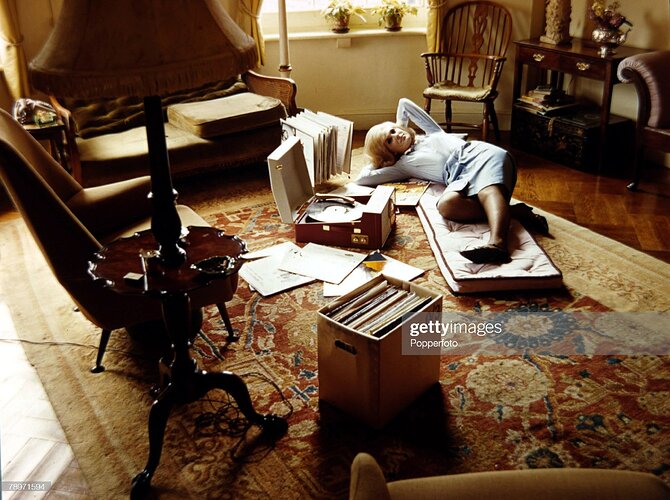 1965, British singer Dusty Springfield relaxing at home listening to music